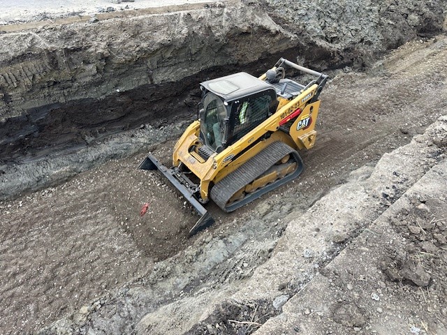 Hi-Tower CAT compact track loader performing earthworks on a construction site.