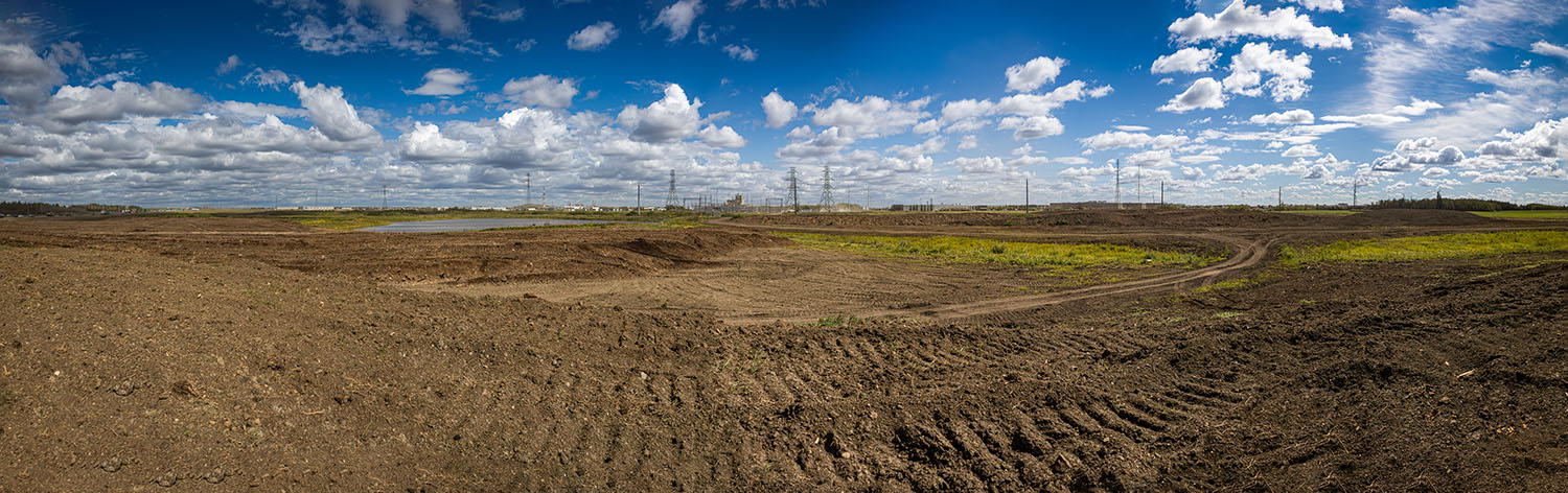 Reclaimed land at the Poundmaker peat fire site in west Edmonton, showing leveled soil and new growth after Hi-Tower’s containment and reclamation work.